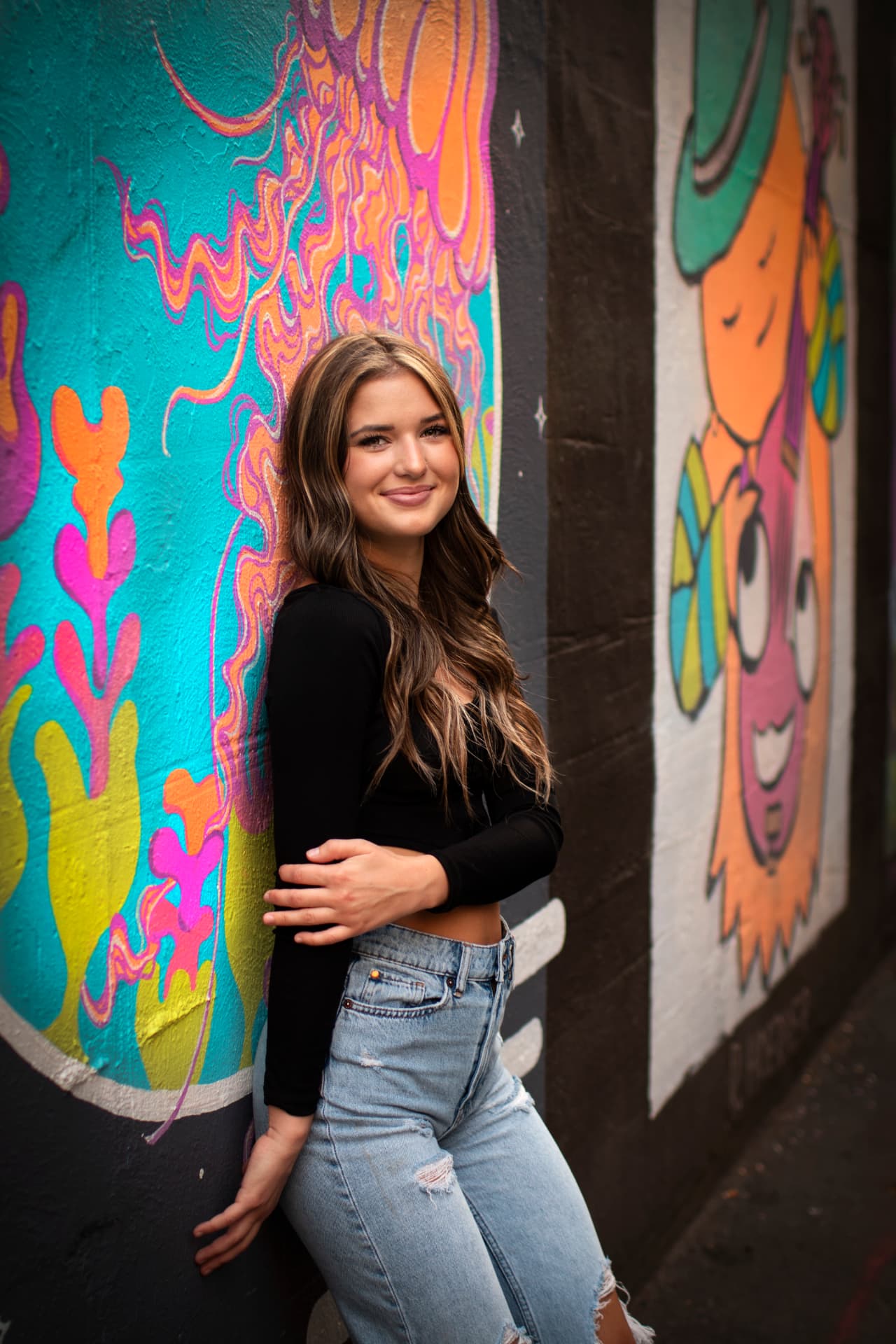 Spokane senior leaning against a colorful downtown mural