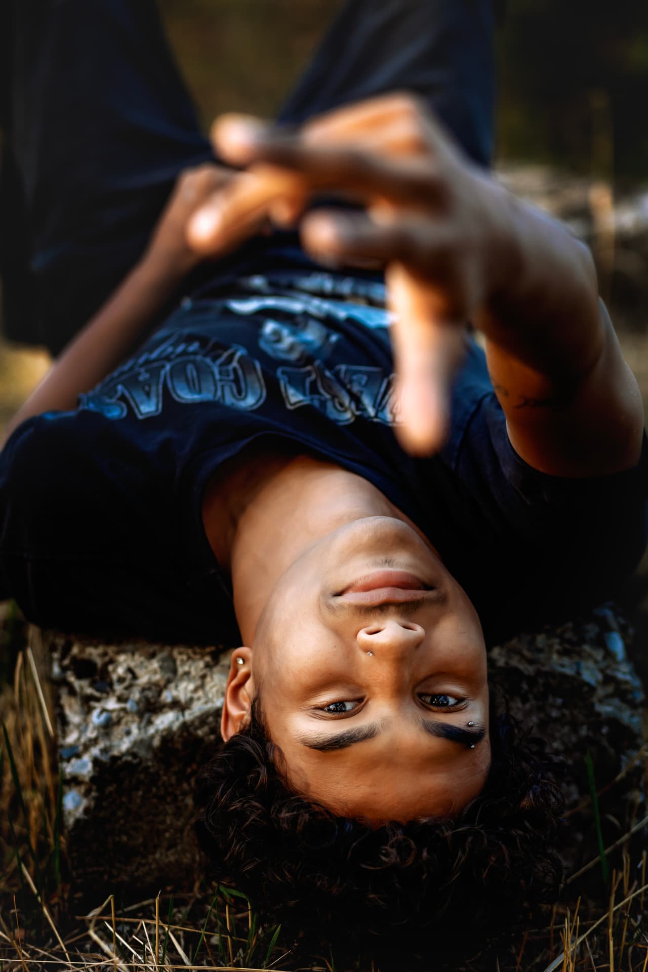 Senior lying back on a sunlit rock, laughing at the camera