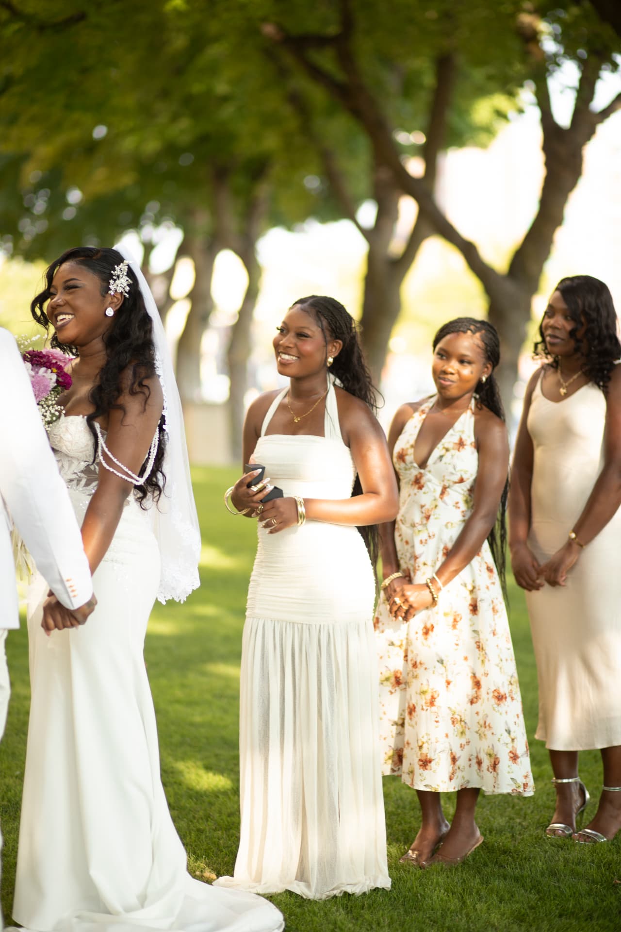 Bride laughing during the ceremony, holding hands with the groom beneath the trees