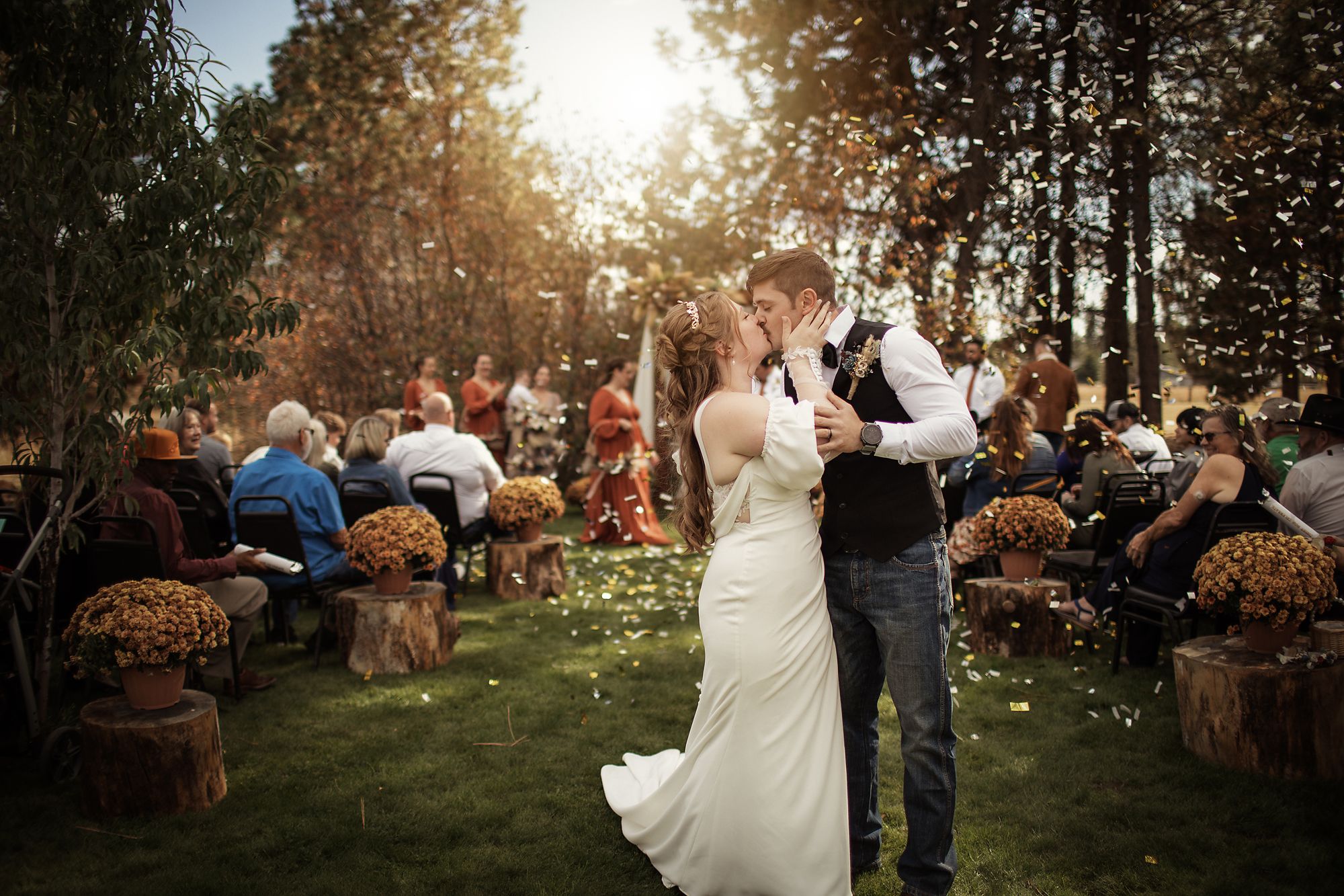 Bride and groom kissing as confetti falls at their outdoor autumn ceremony