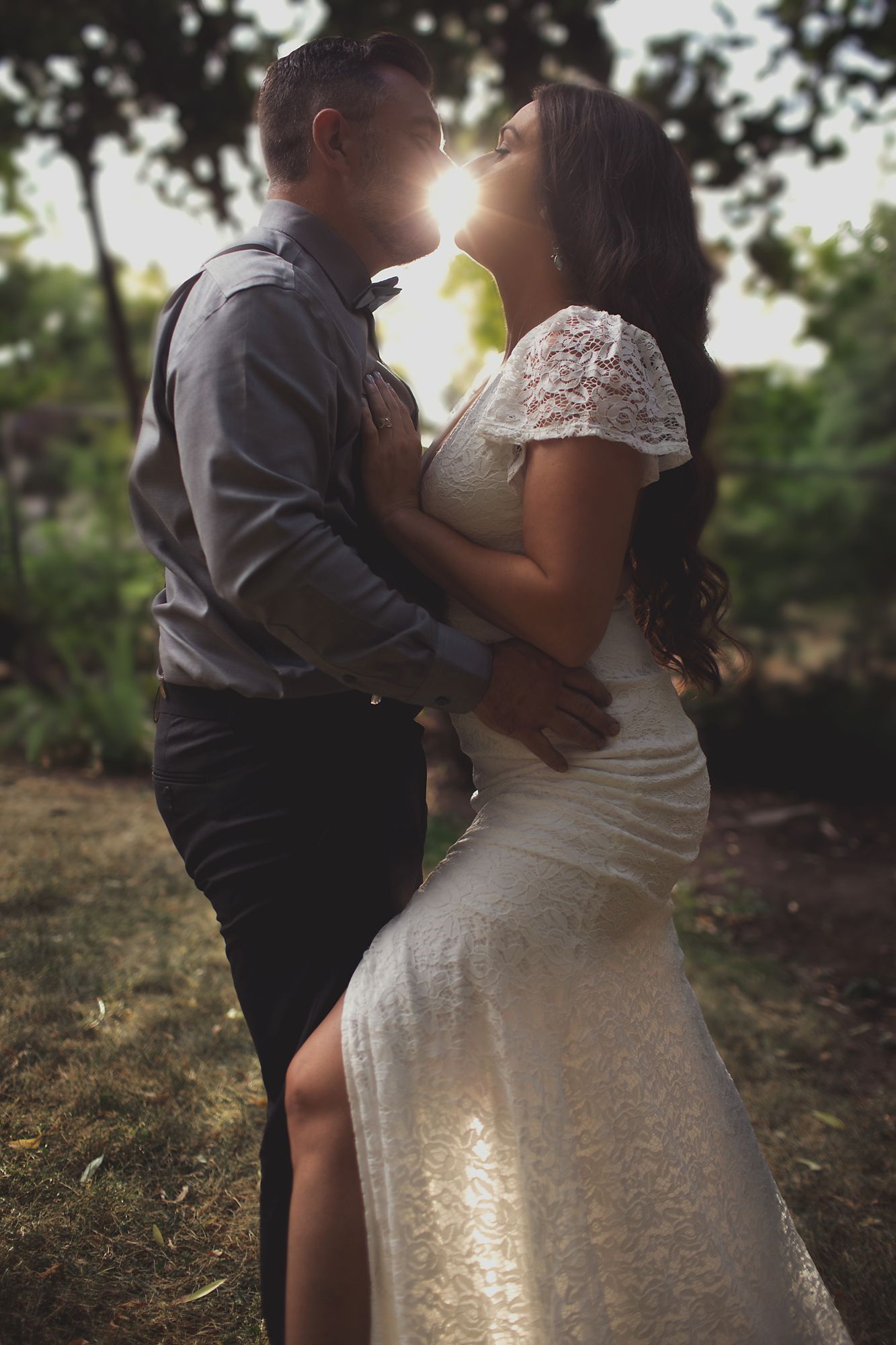 Bride and groom kissing, backlit by the setting sun